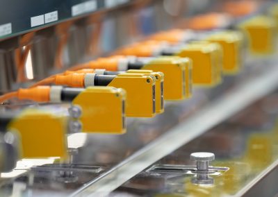 Capteur photoelectrique installe dans une rangee de machines industrielles dans une usine. Capteur photo pour la detection dobjets en usine de machines.