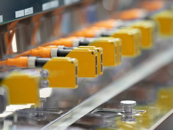 Capteur photoelectrique installe dans une rangee de machines industrielles dans une usine. Capteur photo pour la detection dobjets en usine de machines.